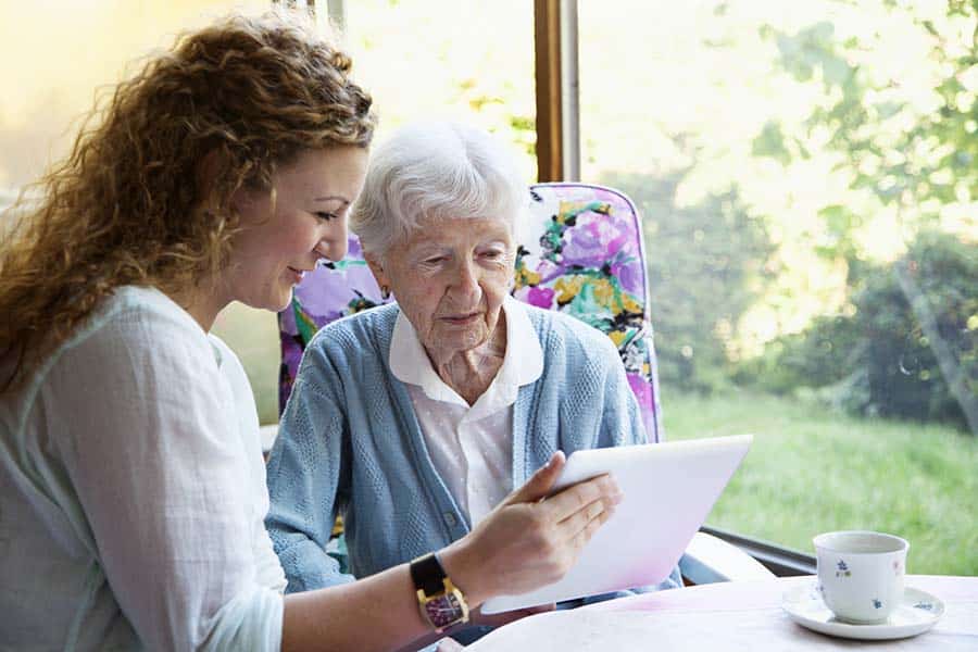 Young woman showing tablet computer to older woman.