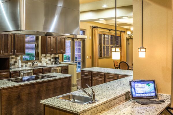 Sonoma House modern community kitchen area with dark wood cabinets, stainless steel fixtures and granite countertops.